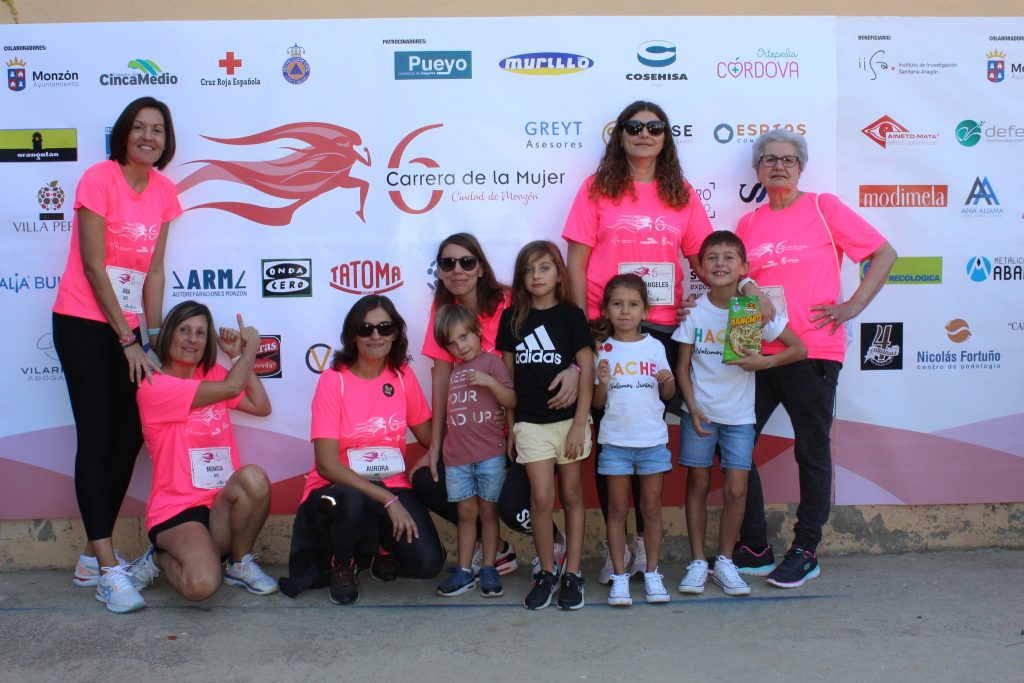 Grupo de chicas y niños en el photocall de la carrera. Las chicas van con camiseta de la carrera, los niños, con camiseta de Hache.