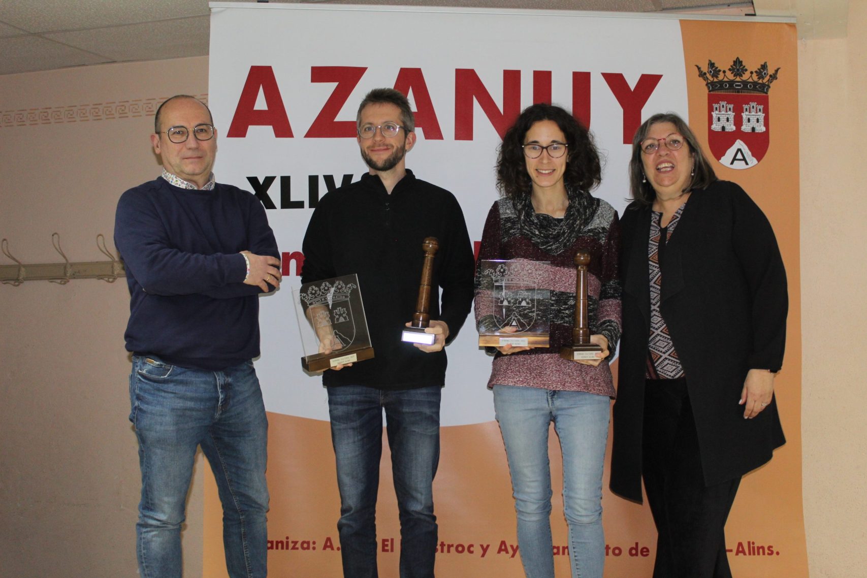 Pedro y Naiara, de la AMO, posan con los recuerdos de la Semana Cultural de Azanuy junto a representantes del ayuntamiento