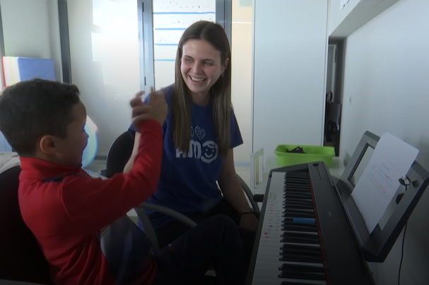 Rayan y su musicoterapeuta sentados frente al piano chocan sus manos